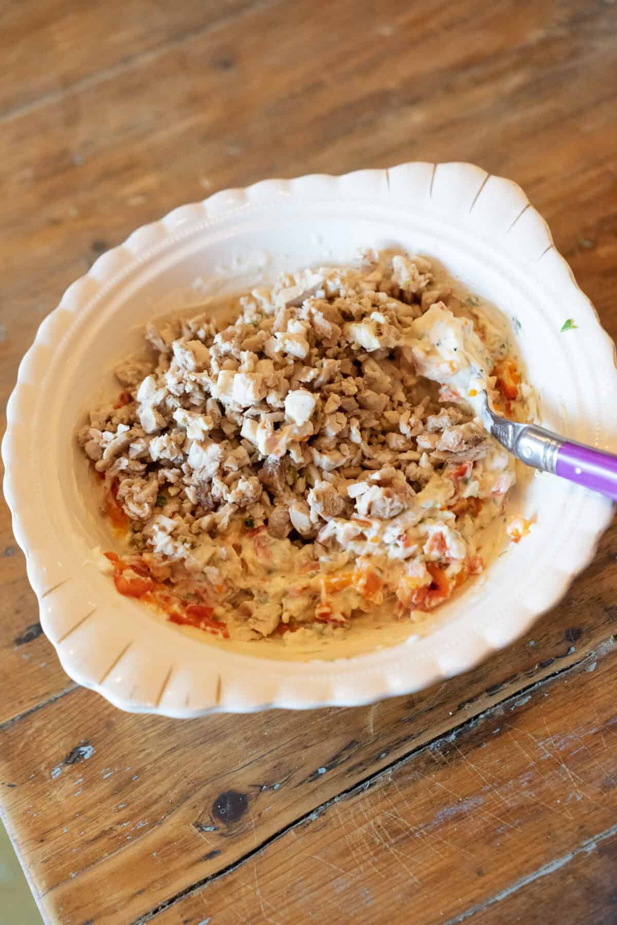 mixing up all the ingredients for a chicken salad with high protein