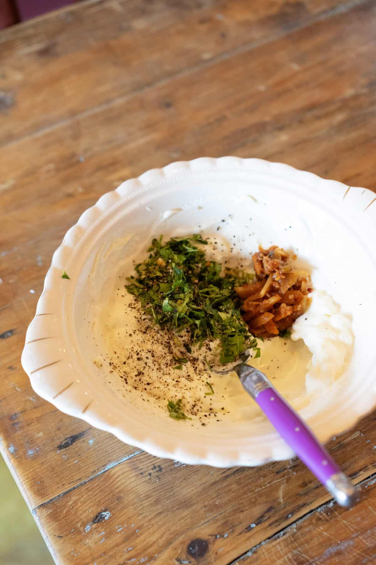 adding herbs and seasoing and kimchi to cream cheese